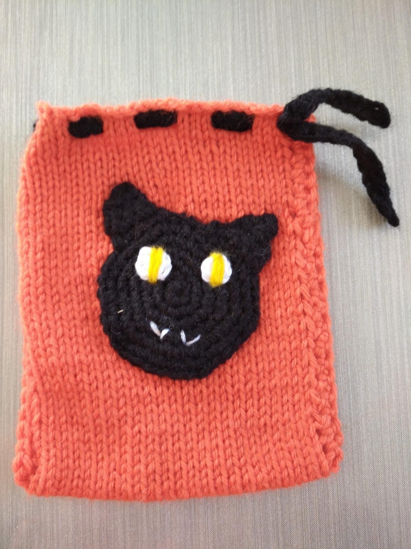 pochette à bonbons tricotée avec motif thématique au crochet cousu dessus